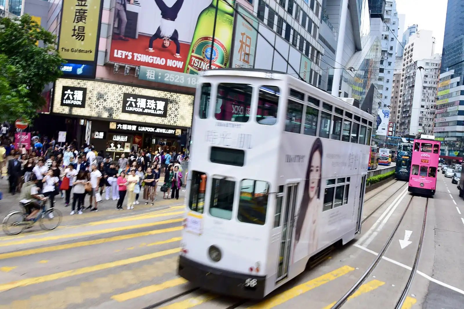 白色雙層電車駛過熱鬧嘅銅鑼灣街頭